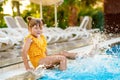 Little preschool girl playing in outdoor swimming pool by sunset. Child learning to swim in outdoor pool, splashing with Royalty Free Stock Photo
