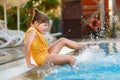 Little preschool girl playing in outdoor swimming pool by sunset. Child learning to swim in outdoor pool, splashing with Royalty Free Stock Photo