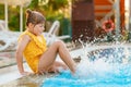 Little preschool girl playing in outdoor swimming pool by sunset. Child learning to swim in outdoor pool, splashing with Royalty Free Stock Photo