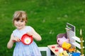 Little preschool girl playing with toy kitchen in garden. Happy toddler child having fun with role activity game Royalty Free Stock Photo