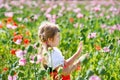 Little preschool girl in poppy field. Cute happy child in red riding hood dress play outdoor on blossom flowering meadow Royalty Free Stock Photo