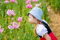 Little preschool girl in poppy field. Cute happy child in red riding hood dress play outdoor on blossom flowering meadow Royalty Free Stock Photo