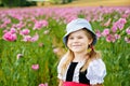 Little preschool girl in poppy field. Cute happy child in red riding hood dress play outdoor on blossom flowering meadow Royalty Free Stock Photo