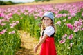 Little preschool girl in poppy field. Cute happy child in red riding hood dress play outdoor on blossom flowering meadow Royalty Free Stock Photo