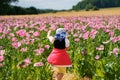 Little preschool girl in poppy field. Cute happy child in red riding hood dress play outdoor on blossom flowering meadow Royalty Free Stock Photo