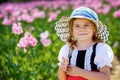 Little preschool girl in poppy field. Cute happy child in red riding hood dress play outdoor on blossom flowering meadow Royalty Free Stock Photo