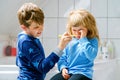 Little preschool girl and preteen school boy brushing teeth. Brother teaching sister brush teeth. Sad upset crying child Royalty Free Stock Photo