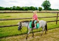 Little preschool girl riding a pony on a farm. Happy lovely child practicing horseback riding. Outdoor summer activities for Royalty Free Stock Photo