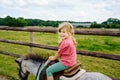 Little preschool girl riding a pony on a farm. Happy lovely child practicing horseback riding. Outdoor summer activities for Royalty Free Stock Photo