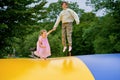 Little preschool girl and school sister jumping on trampoline. Happy funny children, siblings in love having fun with Royalty Free Stock Photo