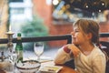 Little preschool girl sitting in restaurant near window decorated for Christmas. Child waiting for food. Happy family Royalty Free Stock Photo