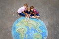 Little preschool girl and two school kids boys with earth globe painting with colorful chalks on ground. Happy earth day