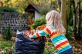 Little preschool girl working with rake in autumn garden. Adorable happy healthy child having fun with helping of fallen leaves Royalty Free Stock Photo