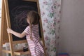 Little Preschool Girl Writing on Blackboard. Toddler girl holding chalk and drawing. Royalty Free Stock Photo