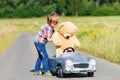 Little preschool kid boy driving big toy car and having fun with playing with his plush toy bear, outdoors. Child Royalty Free Stock Photo