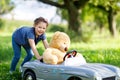 Little preschool kid girl driving big toy car and having fun with playing with big plush toy bear Royalty Free Stock Photo