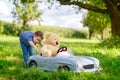 Little preschool kid girl driving big toy car and having fun with playing with big plush toy bea