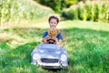 Little preschool kid girl driving big toy car and having fun with playing with big plush toy bear Royalty Free Stock Photo