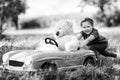Little preschool kid girl driving big vintage old toy car and having fun with playing with big plush toy bear, outdoors Royalty Free Stock Photo