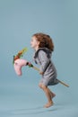 Little girl is hopping on a hobbyhorse, hovering in the air over blue background