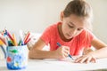 Little preschooler girl diligently drawing something with blue pencil