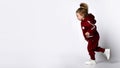 Little preschooler girl wearing warm tracksuit walking over studio copy space