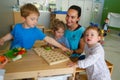 Childrens playing with their teacher at Kindergarten in classroom