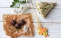 A little present, fresh flowers and some chocolate candies on a white wooden surface