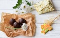 A little present, fresh flowers and some chocolate candies on a white wooden surface