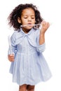 Little pretty fashionable african american girl in blue dress blowing soap bubbles on white background Royalty Free Stock Photo