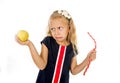 Little pretty female child choosing dessert holding unhealthy but tasty red candy licorice and apple fruit Royalty Free Stock Photo