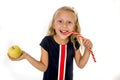 Little pretty female child choosing dessert holding unhealthy but tasty red candy licorice and apple fruit Royalty Free Stock Photo