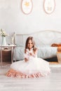 Little pretty girl in a beautiful white dress plays with a toy on the floor in the children`s bedroom Royalty Free Stock Photo