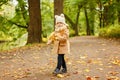Little pretty girl in a beige coat, autumn in the park collects Royalty Free Stock Photo