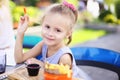 Little pretty girl eating rench fries with sauce at street cafe outside. Royalty Free Stock Photo