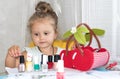 Little pretty girl examines bottles of nail polish