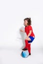 Little pretty girl in a football uniform and with ball on white background looks to the side. Women`s football concept for kids Royalty Free Stock Photo