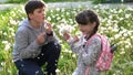 Little pretty girl and her brother in green field are playng with dandelions. Children in country. Beautiful flora