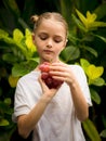 Little pretty girl holding bunch of red grapes near her face. Selected focus. Green tropical leaves background. Organic fruit Royalty Free Stock Photo