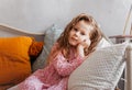 A little pretty girl rests on a pillow on a bed in a children`s bedroom. Thoughtfulness and dreaminess Royalty Free Stock Photo