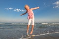 Little pretty girl on summer beach. Cheerful little girl dancing on the background of blue sky and summer sea