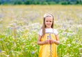 Little pretty girl in yellow Russian dress picking flowers in field of wild flowers on summer day Royalty Free Stock Photo