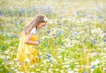 Little pretty girl in yellow Russian dress picking flowers in field of wild flowers on summer day Royalty Free Stock Photo