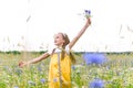 Little pretty girl in yellow Russian dress picking flowers in field of wild flowers on summer day Royalty Free Stock Photo