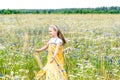 Little pretty girl in yellow Russian dress picking flowers in field of wild flowers on summer day Royalty Free Stock Photo