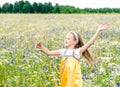 Little pretty girl in yellow Russian dress picking flowers in field of wild flowers on summer day Royalty Free Stock Photo