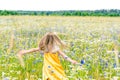 Little pretty girl in yellow Russian dress picking flowers in field of wild flowers on summer day Royalty Free Stock Photo