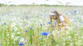 Little pretty girl in yellow Russian dress picking flowers in field of wild flowers on summer day Royalty Free Stock Photo