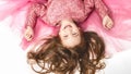 Little Princess. Portrait of a cute Caucasian little laughing girl in an evening bright pink dress lies on a white background. Royalty Free Stock Photo