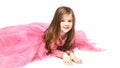 Little Princess. Portrait of a cute Caucasian little laughing girl in an evening bright pink dress lies on a white background. Royalty Free Stock Photo